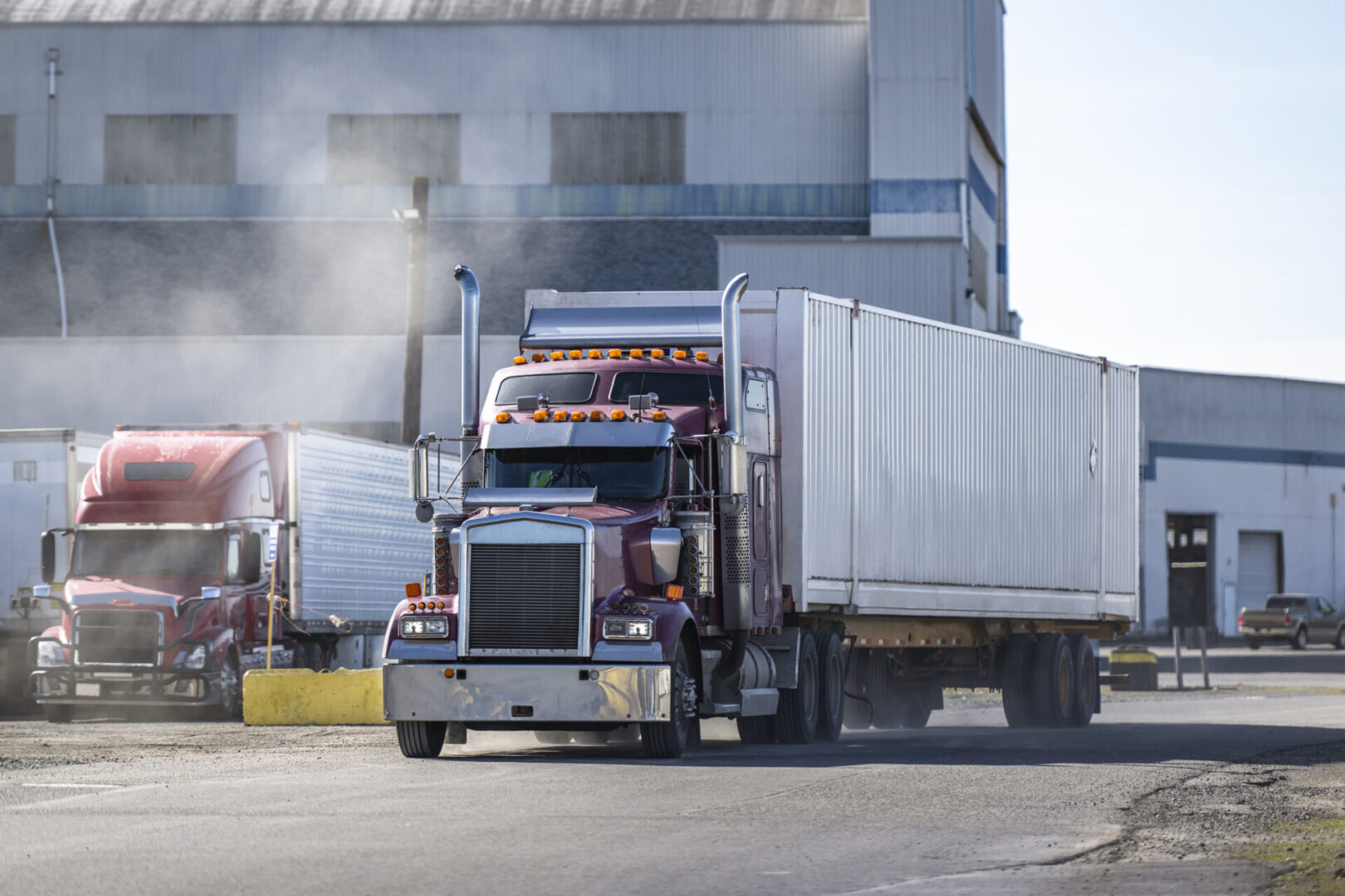 Red and white trucks outside industrial building.