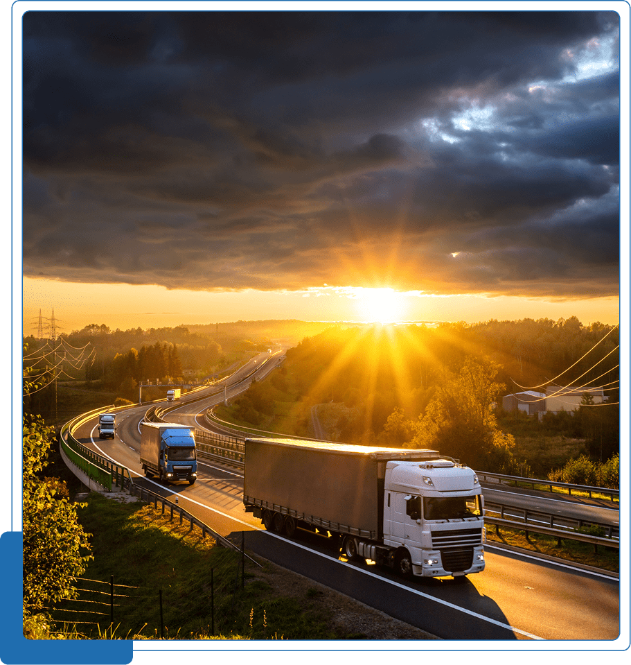 Trucks driving on highway at sunset.
